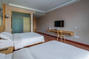 a hotel room with two beds and a desk at Meiwan Inn in Jiaxing