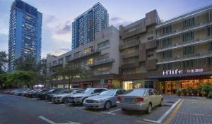 a parking lot with cars parked in front of a building at H Life Hotel in Shenzhen