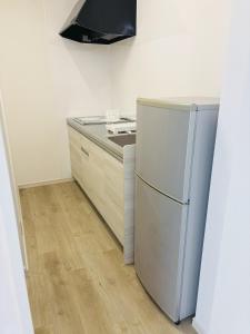 a kitchen with a stove and a refrigerator at 浦添民泊ejuイージュ in Urazoe