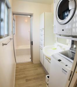 um banheiro branco com pia e chuveiro em Jazz 喫茶 Eju イージュ B&B em Urazoe