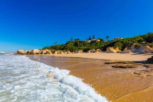a sandy beach with waves coming in from the ocean at Vila Joya in Albufeira