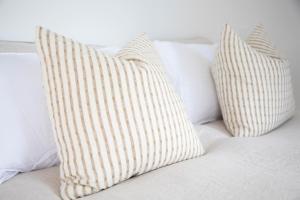 two white pillows sitting on a bed at The Coconut Hut Papamoa Beach in Tauranga