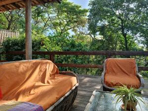 two chairs and a glass table on a wooden deck at Bangalô Rústico Duplex - Retiro Andaluz in Brumadinho