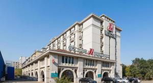 ein großes weißes Gebäude mit davor geparkten Autos in der Unterkunft Jinjiang Inn Shenyang Xinggong North Street METRO in Shenyang