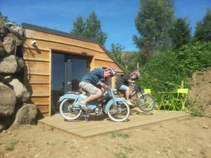 two people riding bikes on a ramp in front of a tiny house at Domaine de l'Ours / Camping Lodge in Saint-Urcize