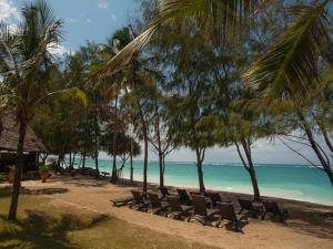 a beach with chairs and palm trees and the ocean at Bahari Dhow Beach Villas in Diani Beach