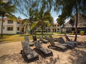 a group of chairs sitting in the sand in front of a building at Bahari Dhow Beach Villas in Diani Beach
