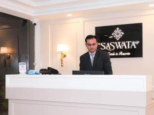 Ein Mann im Anzug, der hinter einem Podium steht. in der Unterkunft Saswata Hotels By Kamay Group in Ayodhya