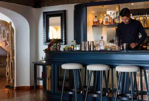 a man standing behind a bar with stools at Vila Joya in Albufeira