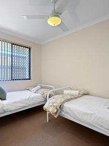 zwei Betten in einem weißen Zimmer mit Fenster in der Unterkunft Seascapes And Beaches in Falcon