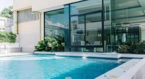 une maison avec piscine devant un immeuble dans l'établissement Aramis Hotel, à Nakhon Sawan