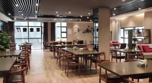 Un restaurante con mesas y sillas en una sala. en Shenzhen Hanyong Hotel Fuyong Branch, en Fenghuangwei