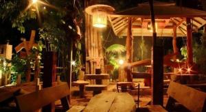 ein Zimmer mit einem Holztisch und Bänken in der Nacht in der Unterkunft Tambai Resort in Ban Khaek