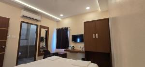 a hotel room with a bed and a television at sri selvaas inn in Kanchipuram