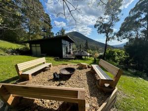 twee banken in een tuin met een vuurplaats bij Sunset View House in Warburton
