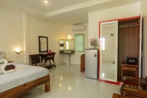 a bedroom with a bed and a refrigerator in it at The Golden Beach Resort Naiyang in Nai Yang Beach