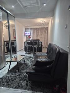 ein Wohnzimmer mit einem schwarzen Ledersofa und einem TV in der Unterkunft Mulberry Suites in Cleethorpes