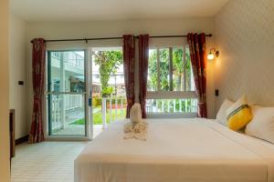 a bedroom with a large bed and a large window at The Golden Beach Resort Naiyang in Nai Yang Beach