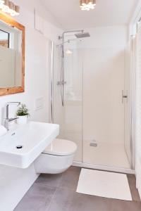 een witte badkamer met een wastafel en een douche bij Weinberg Lodge - Kellerstöckl in Klöch