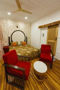 a bedroom with a bed and two chairs and a table at The Shesh Bagh Boutique - Garden Stay Near Dal Lake & Mughal Garden in Srinagar