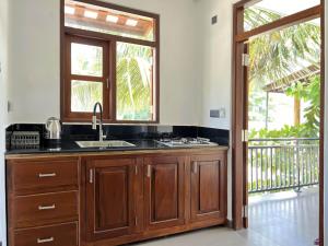 a kitchen with a sink and a door to a balcony at Kiyoko Villa in Maha Induruwa