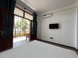 a bedroom with a bed and a tv on a wall at Kiyoko Villa in Maha Induruwa