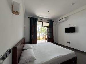 a bedroom with a large bed and a television at Kiyoko Villa in Maha Induruwa