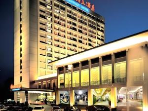 ein großes Gebäude mit auf einem Parkplatz abgestellten Autos in der Unterkunft New Century Hotel Ninghai in Shang-ts'un