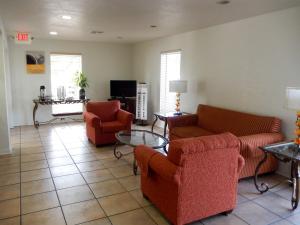 sala de estar con sofás, sillas y TV en Motel 6-Luling, LA, en Luling