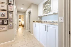 Phoenix X 104 condo في شاطئ أورانج: مطبخ بدولاب بيضاء وأرضية بلاط