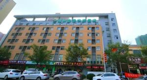 ein großes Gebäude, vor dem Autos parken in der Unterkunft GreenTree Inn Wuxi Huishan District Xizhang Metro Station Express Hotel in Wuxi