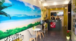 zwei Personen an einer Bar in einem Hotel mit einem Strandwandbild in der Unterkunft Shell Hotel Shanghai Baoshan Meilanhu Luosheng Road in Luodian