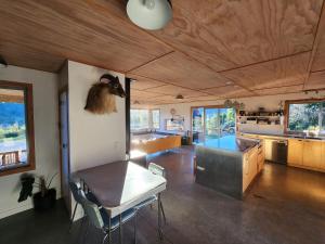 a living room with a table and a kitchen at Stony Ridge Summer Stay in Motueka