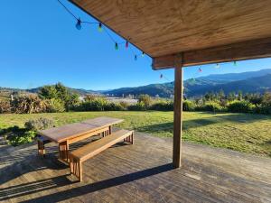 a picnic table on a deck with a view of a field at Stony Ridge Summer Stay in Motueka