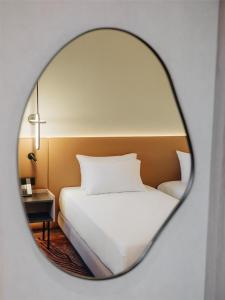 um quarto com uma cama branca e um espelho redondo em Hyatt Place Tallinn em Taline