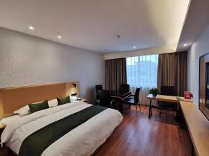 a hotel room with a large bed and a desk at GreenTree Inn Ganzhou Gan County Bus Station in Meilin +233 photos