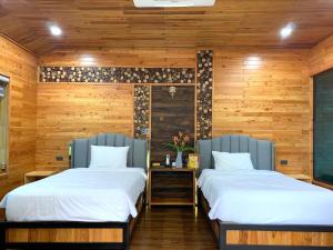 two beds in a room with wooden walls at Kovie Hoa Lac Xanh Resort in Nam Giao