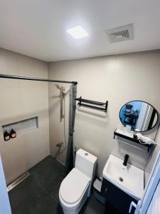 a bathroom with a toilet and a sink and a mirror at Homey Hideout- Athena and Noah Units in Magalang +23 photos