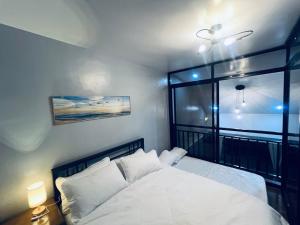 a bedroom with a white bed and a window at Homey Hideout- Athena and Noah Units in Magalang