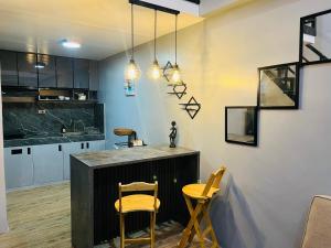 a kitchen with a counter and two yellow chairs at Homey Hideout- Athena and Noah Units in Magalang