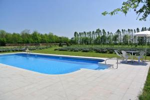 a swimming pool with two chairs and an umbrella at Agriturismo Domus Magna in Povoletto