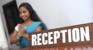 eine Frau steht neben einem Schild mit der Aufschrift „Rezeption“ in der Unterkunft The MGS Hotel in Kadirandola