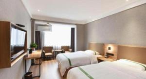 ein Hotelzimmer mit zwei Betten und einem Schreibtisch in der Unterkunft GreenTree Inn Hefei Chenghuangmiao San Xiao Kou Subway Station Hotel in Hefei