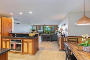 een keuken met houten kasten en een eetkamer bij Nihi Kai 806 condo in Koloa +26 foto's