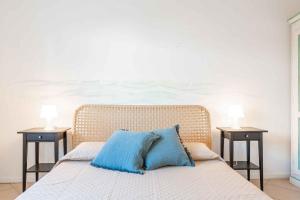 ein Bett mit blauen Kissen und zwei Tischen in der Unterkunft Holiday home in Baja Sardinia 30355 in Baja Sardinia