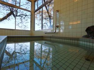 un charco de agua en un baño con ventanas en 眺望の湯宿弁天, en Tonami 21 fotos más