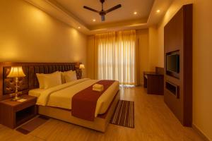 una habitación de hotel con una cama y un televisor en Xenious Opulent Hamirpur, en Hamīrpur