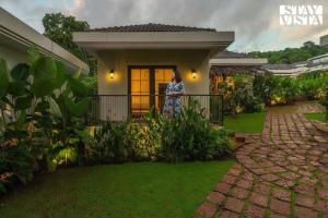 eine Frau steht auf dem Balkon eines Hauses in der Unterkunft StayVista at Kuhu Natures Resort with BBQ, Pool in Mandrem