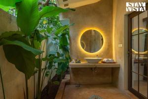 ein Badezimmer mit einem Waschbecken, einem Spiegel und einer Pflanze in der Unterkunft StayVista at Kuhu Natures Resort with BBQ, Pool in Mandrem + 28 Fotos