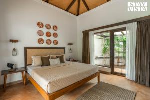 ein Schlafzimmer mit einem Bett und einem großen Fenster in der Unterkunft StayVista at Kuhu Natures Resort with BBQ, Pool in Mandrem